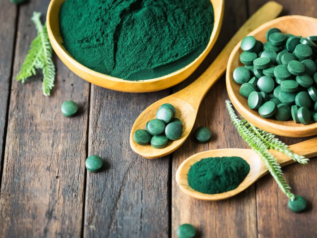 Cucchiai e contenitori con integratori di alga spirulina in polvere e compresse